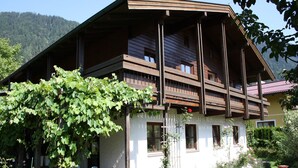 A two-story wooden house with a balcony, surrounded by a garden with various plants and flowers. - Country House Goldegg near Ski Slopes (Goldegg - Weng)