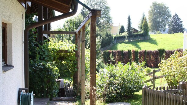 A covered outdoor area with a garden, a wooden fence, and a hose reel on the wall. - Country House Goldegg near Ski Slopes (Goldegg - Weng)