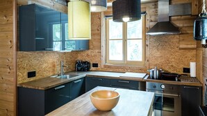 A modern kitchen with wooden walls, a large window, and stainless steel appliances.