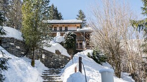 A stone staircase leading to a building with a snow-covered roof, surrounded by trees.