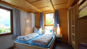 A wooden cabin bedroom with a bed, nightstands, and a wardrobe. - Chalet in Neukirchen near Ski Lifts (Neukirchen am Großvenediger)