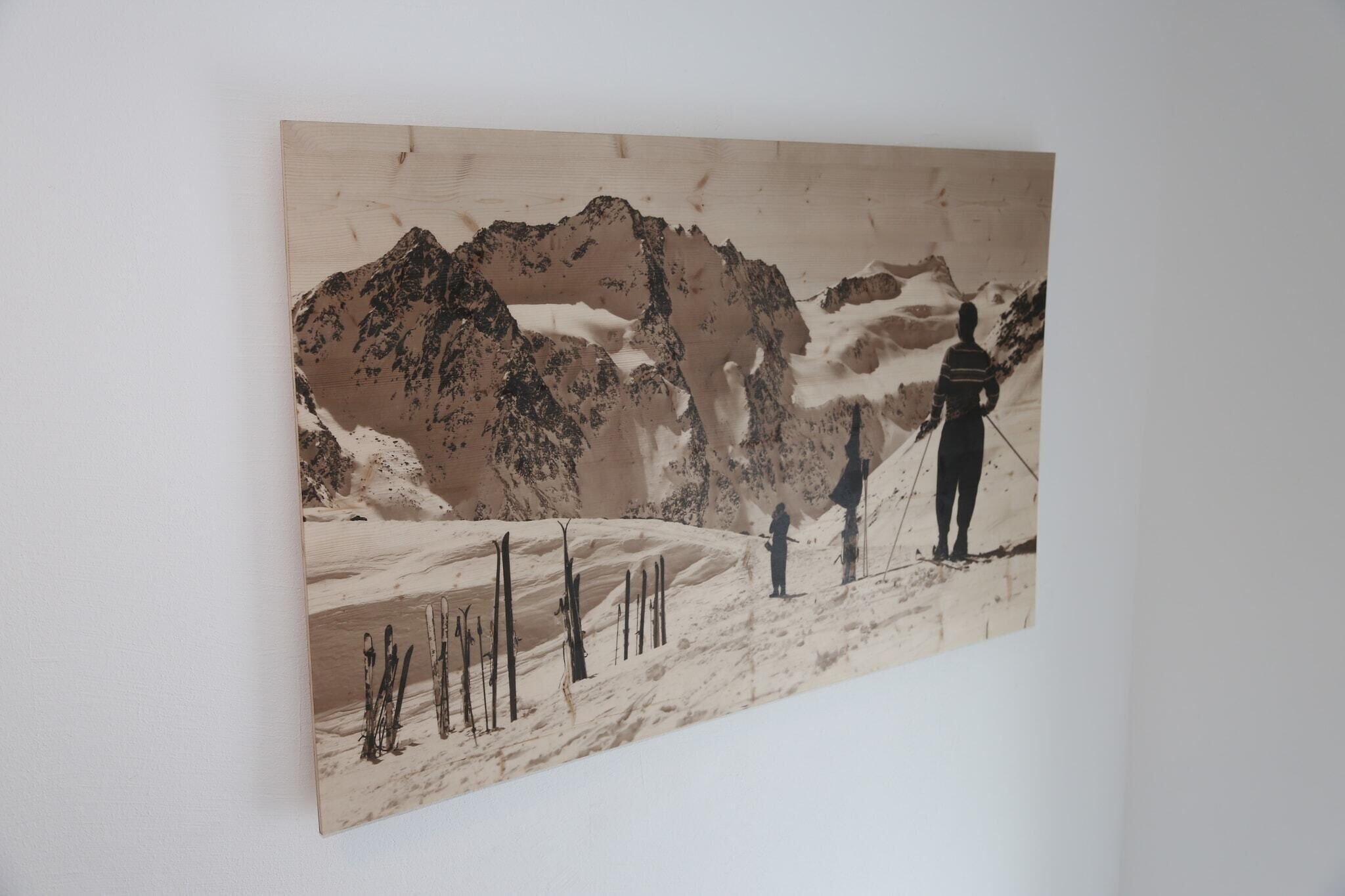 Un tableau représentant un paysage de montagne enneigé, avec une personne debout sur une pente.