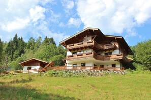 Un chalet a due piani con un balcone in legno e un muro in pietra di fronte.