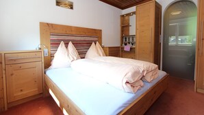 A bedroom with a wooden bed, a nightstand, a dresser, and a mirror. - Chalet in Maria Alm near Hochkönig Ski Lift (Maria Alm)