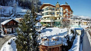 A multi-story hotel with a ski lift in the background, surrounded by snow-covered trees and mountains. - Apartment in Kaltenbach near Ski Lift (Kaltenbach)