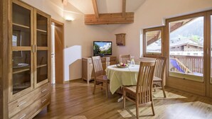 A dining area with a wooden table and chairs, a television, and a view of a mountain landscape through a window. - Apartment in Kaltenbach near Ski Lift (Kaltenbach)