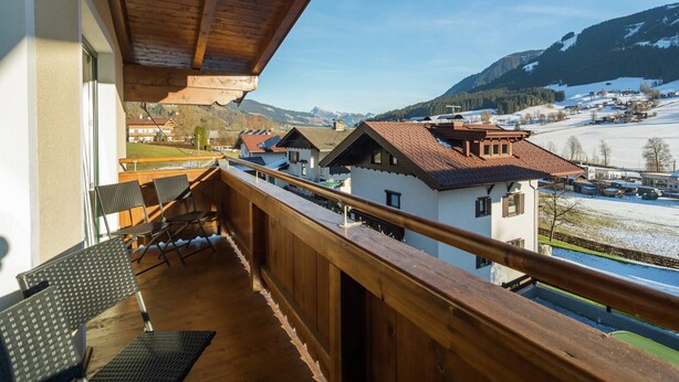 A wooden balcony with a view of a snow-covered landscape and houses. - Holiday Home Brixen near Skiwelt Slopes (Brixen im Thale)