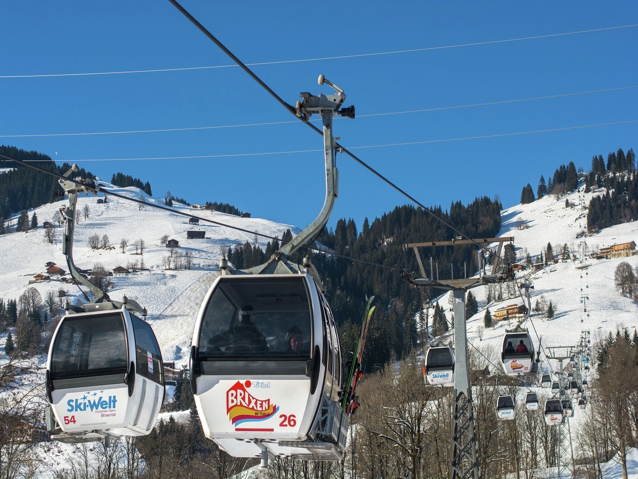 Hiihtohissi, jonka gondolien kyljissä on tekstit »Skiwelt 54» ja »Brixen 26».