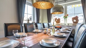 A dining area with a long wooden table set for six, leather chairs, and two large textured pendant lights. - Holiday Home Brixen near Skiwelt Slopes (Brixen im Thale)
