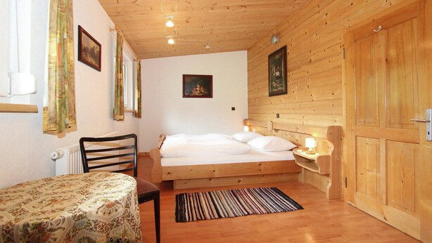 Una habitación con paneles de madera, una cama, una mesa y una silla.