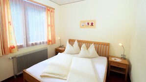Een hotelkamer met een groot bed, twee nachtkastjes, een radiator en een raam met gordijnen.