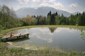 A serene lake with a wooden dock and a person sitting on it.