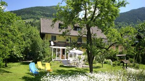 Ein Haus mit Terrasse, Gartenmöbeln und einem Garten mit weißen Blumen.