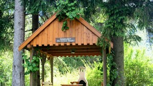 A wooden gazebo with benches and a table, surrounded by trees. - Holiday Home in Hermagor near Nassfeld Ski Area (Hermagor)