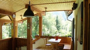 A wooden interior with a dining table and benches, large windows, and a ceiling fan. - Holiday Home in Hermagor near Nassfeld Ski Area (Hermagor)