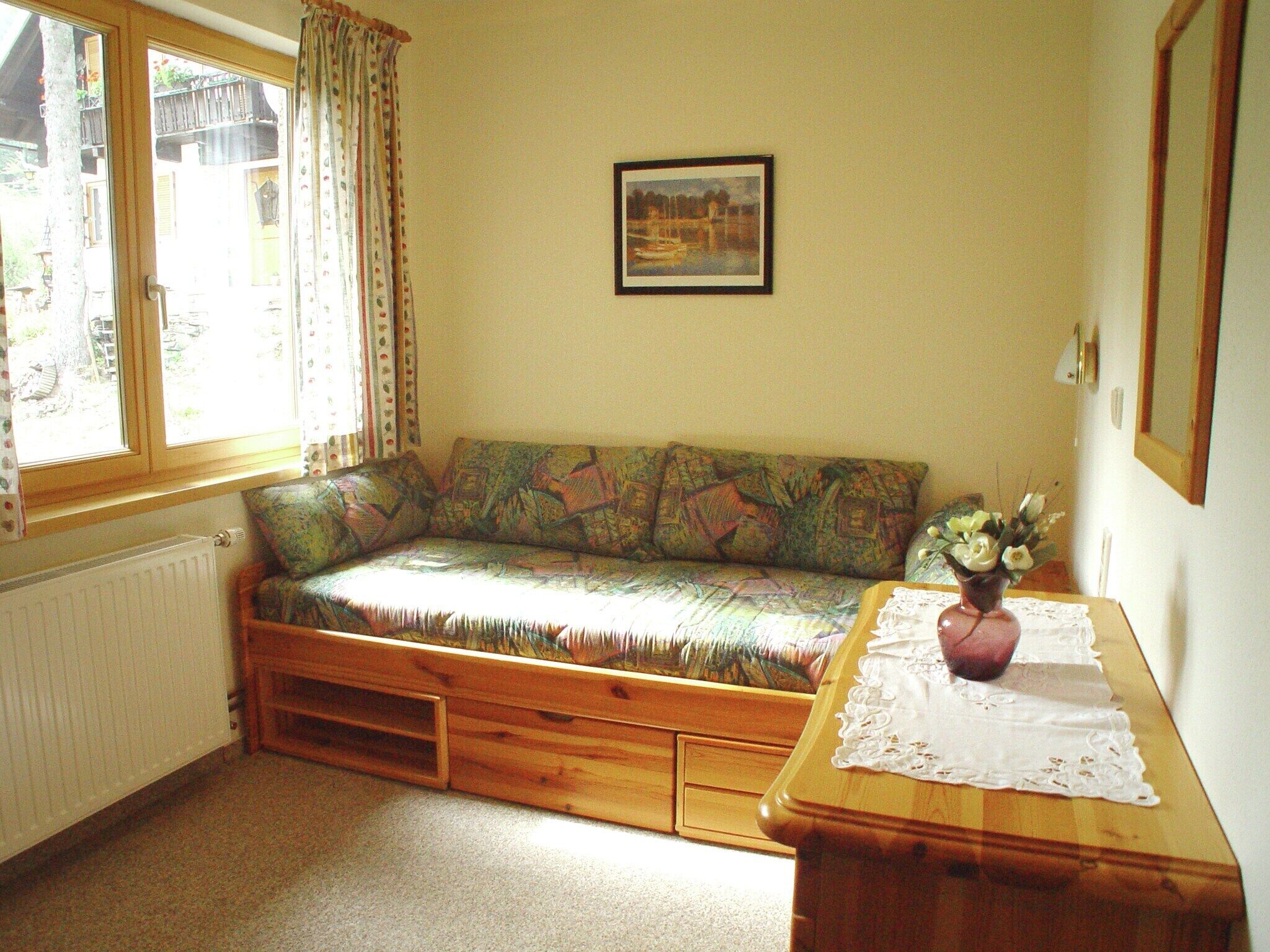 A cozy room with a built-in sofa, a wooden table with a vase, and a framed picture on the wall.