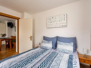 A bedroom with a bed, pillows, a bedside table, a lamp, and a wall-mounted artwork. - Apartment in Tröpolach near Nassfeld (Tröpolach)