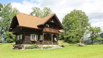 A wooden house with a sloped roof, a balcony, and a stone foundation.