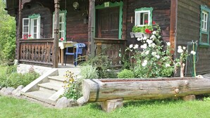 A wooden house with a porch, steps, and a garden.