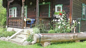 A wooden house with a porch, steps, and a garden.