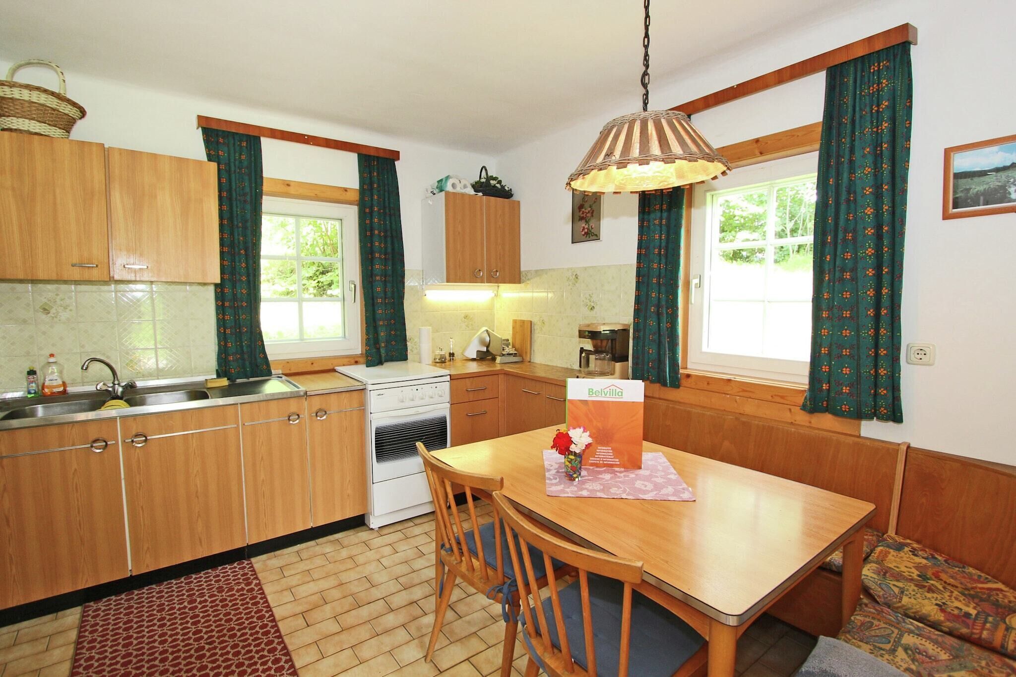 Een keuken met houten kastjes, een fornuis en een eettafel met stoelen.