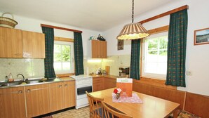 A kitchen with wooden cabinets, a stove, and a dining table with chairs.