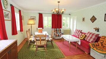 A cozy living room with a dining table, chairs, a sofa, and a coffee table.