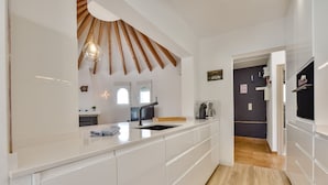 A modern kitchen with white cabinetry, a wooden ceiling, and a built-in oven.