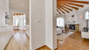 A spacious living area with a fireplace, wooden beams, and a modern kitchen.