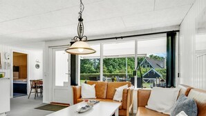 A modern interior with a white table, leather sofa, and a hanging light fixture.