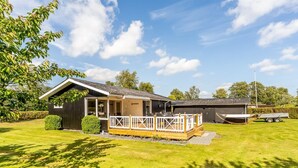 A single-story house with a deck, a garage, and a well-maintained lawn.