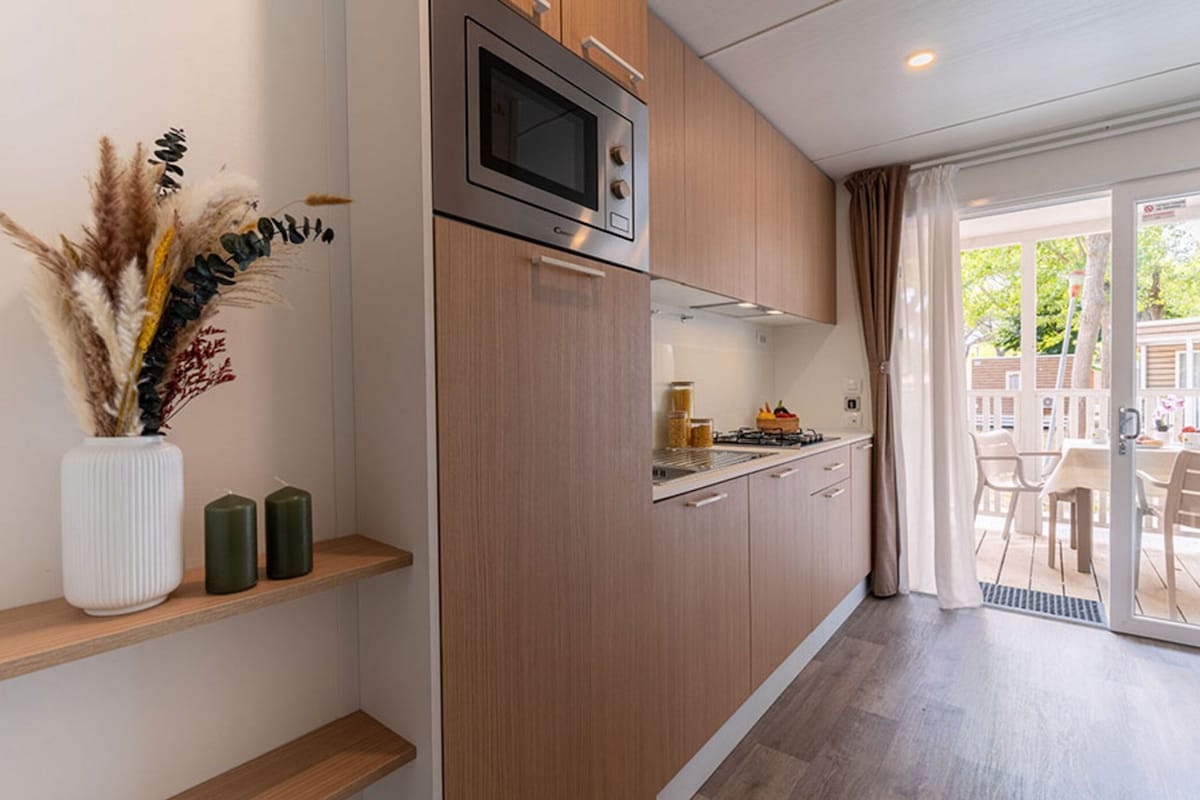 Una cocina moderna con armarios de madera, un microondas integrado y un comedor con mesa y sillas.
