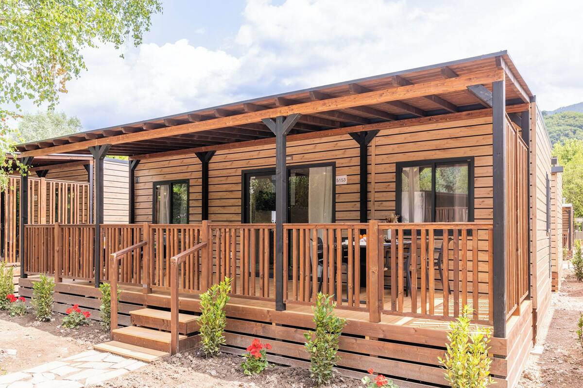 A wooden cabin with a deck, a staircase, and a number '5153' sign.