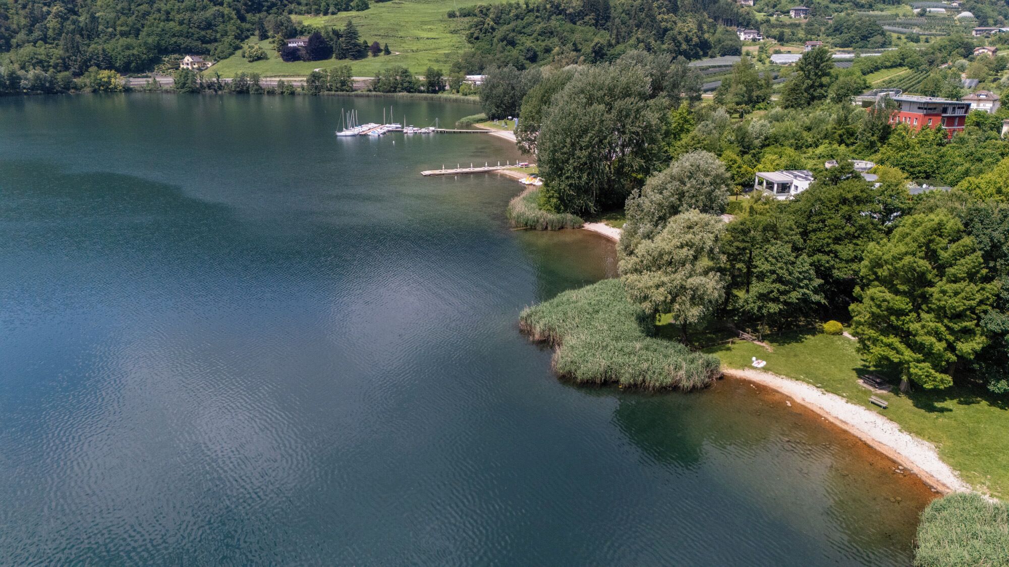 A lake with boats, a dock, and surrounding greenery.