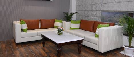 A modern living room with a white sofa, brown cushions, a white coffee table, and a potted plant.