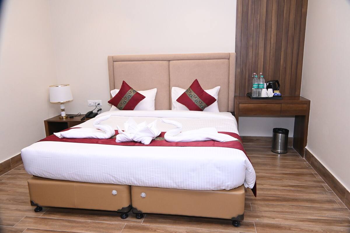 A neatly made bed with white linens, two decorative pillows, a bedside table with a lamp, and a small tray with toiletries.