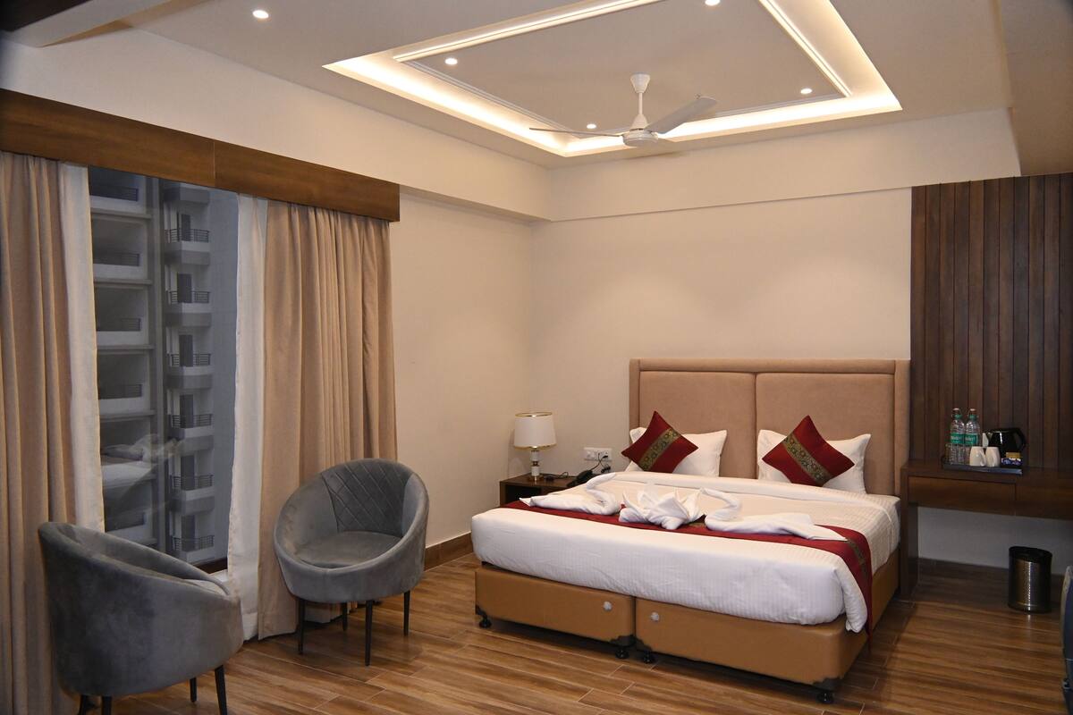 A hotel room with a bed, a chair, a nightstand, and a ceiling fan.