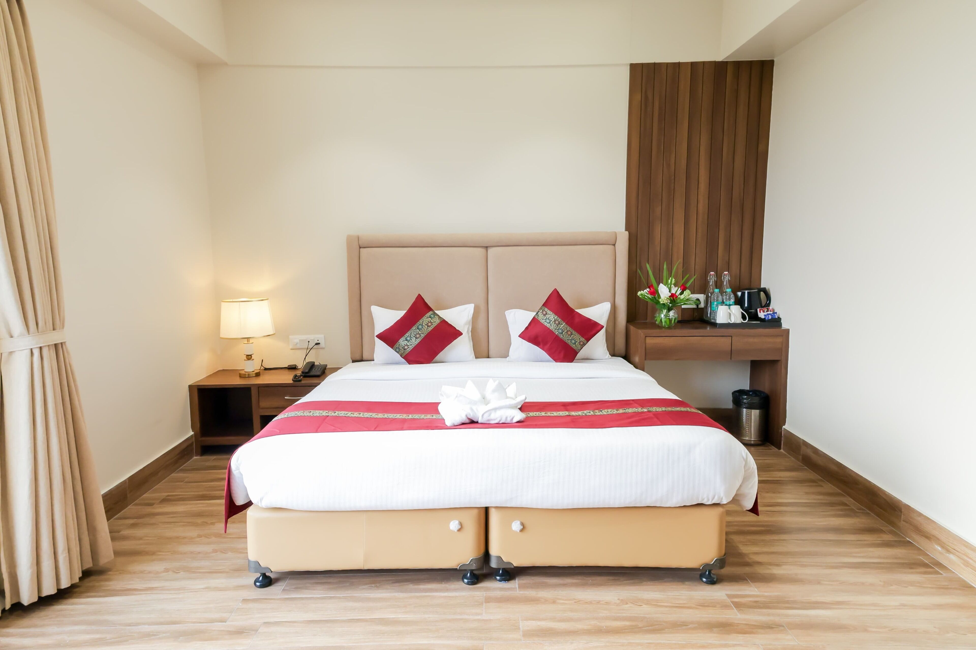 A hotel room with a bed, bedside table, lamp, and a small shelf with toiletries.