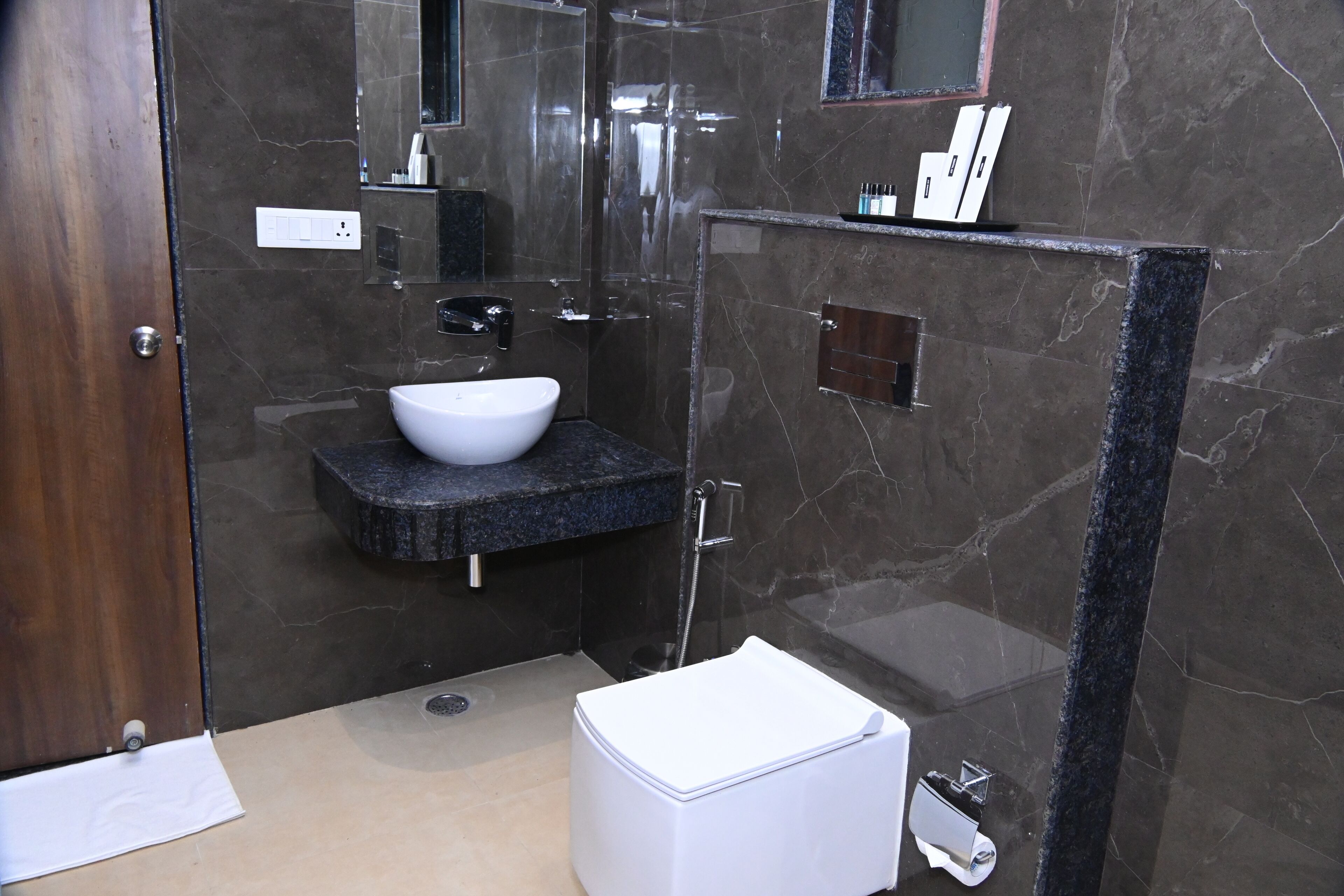 A modern bathroom with a marble sink, a toilet, and a glass shower enclosure.