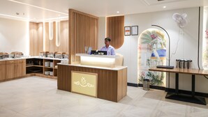 A reception area with a wooden reception desk, a counter with food containers, and a wall with framed certificates. - Hotel The Rising Banaras (Varanasi)