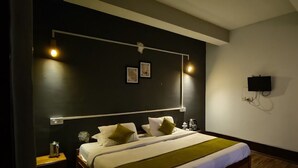 A hotel room with a bed, bedside table, wall-mounted TV, and artwork. - Hotel Valley View by Ravongla Star (Gyalshing)