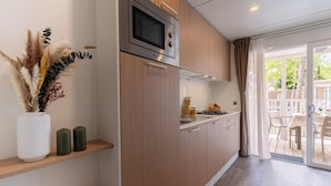 Een moderne keuken met houten kasten, een ingebouwde magnetron en een eethoek met tafel en stoelen.