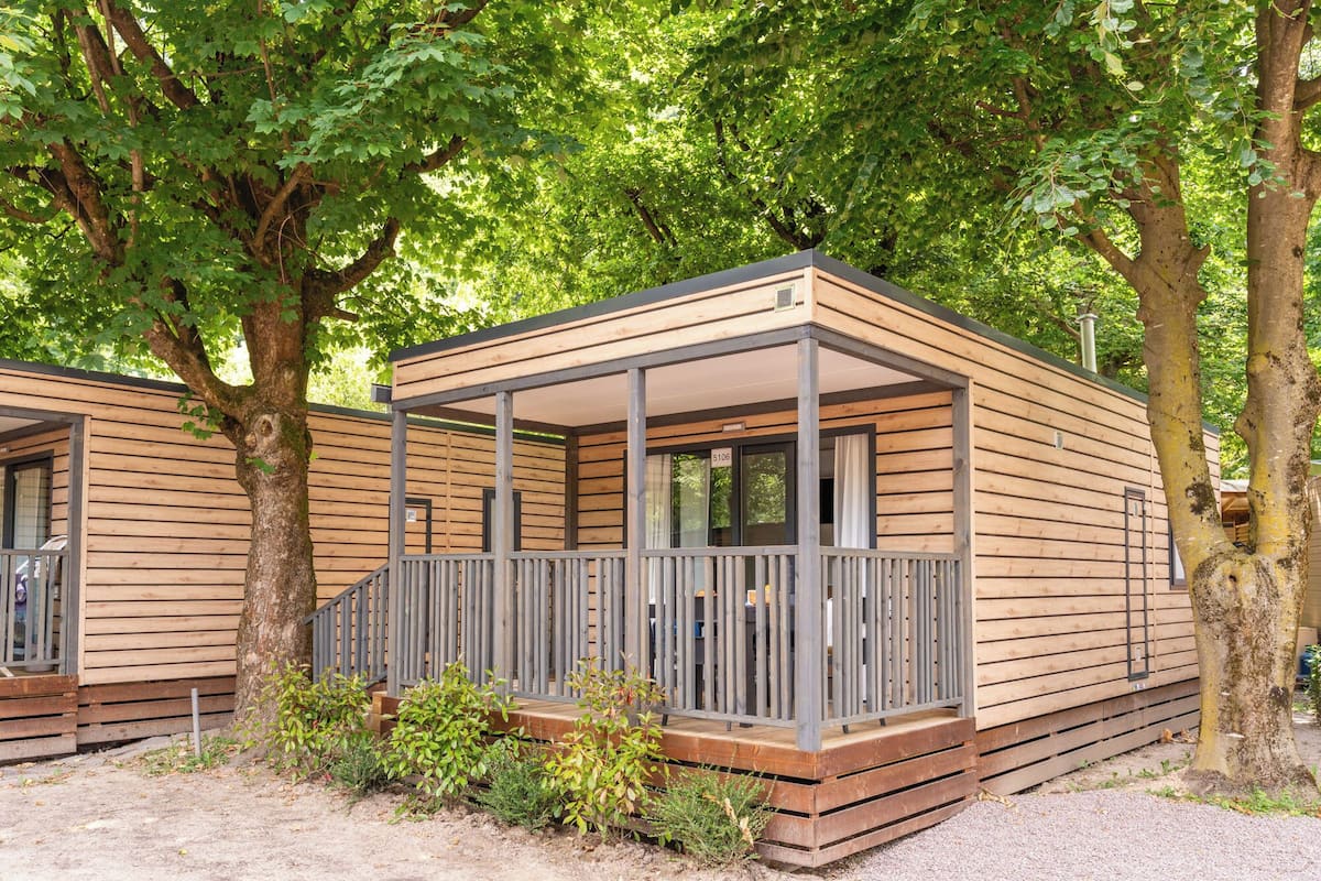 Een houten hut met een balkon, omringd door bomen.