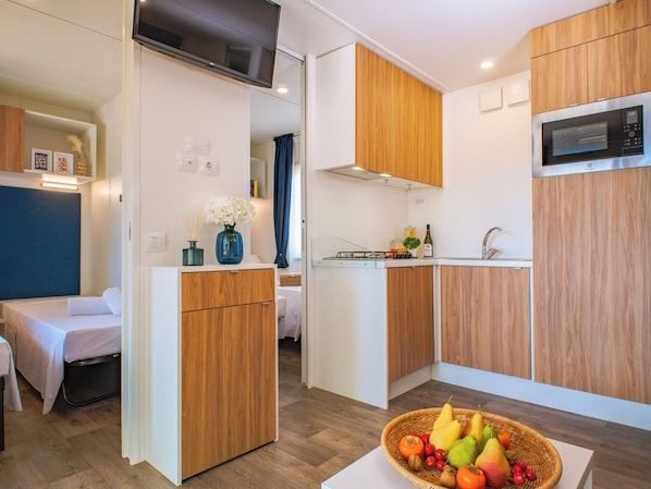 Une cuisine compacte dotée de meubles en bois, d’un four à micro-ondes et d’un coin repas avec une table et des chaises.