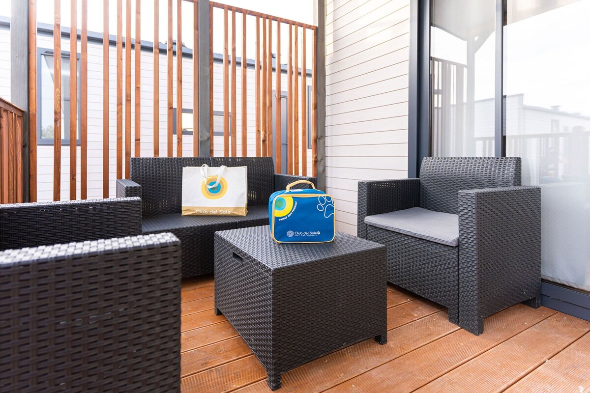 Un balcon avec des meubles en osier, un sac et une fenêtre.