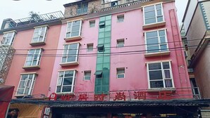 A pink building with multiple windows and a storefront. - Kunming Panju Hotel (Kunming)