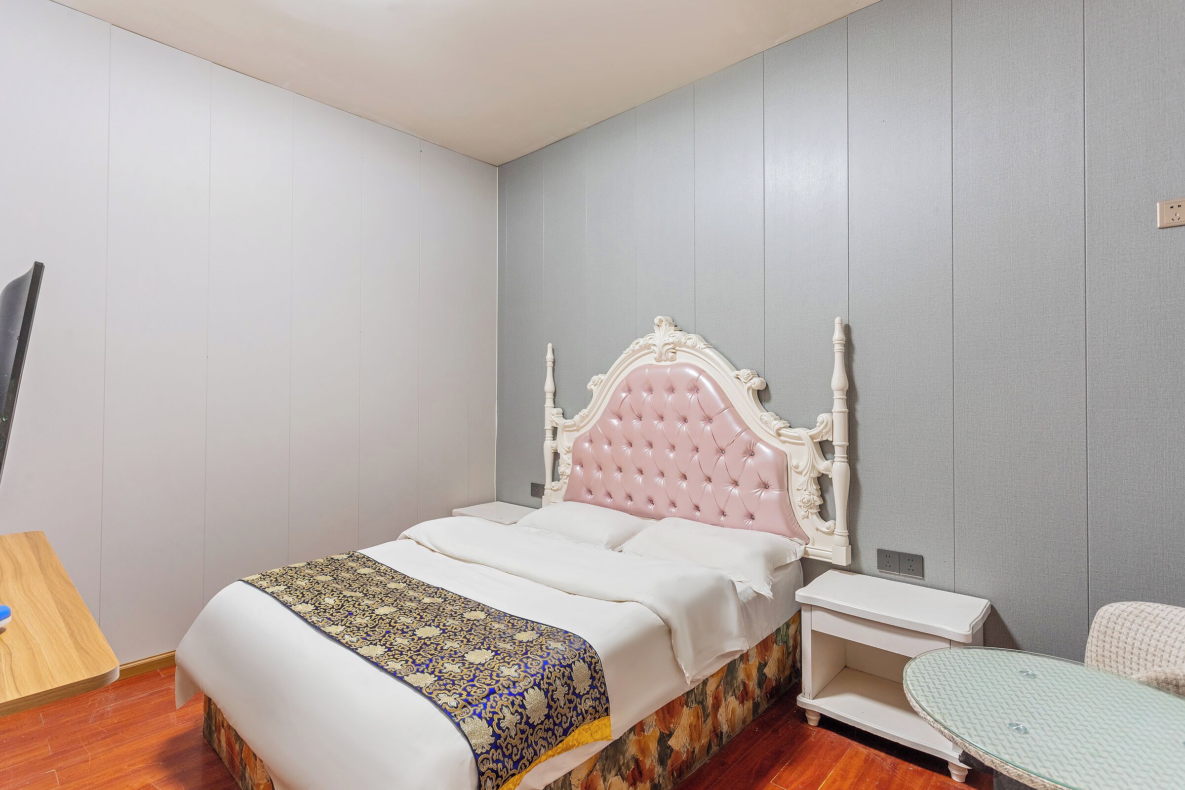 Une chambre à coucher bien rangée, avec un lit, une table de chevet et une petite table.