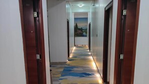 A hotel hallway with a patterned carpet, wooden doors, and a ceiling light. - Kunming Panju Hotel (Kunming)