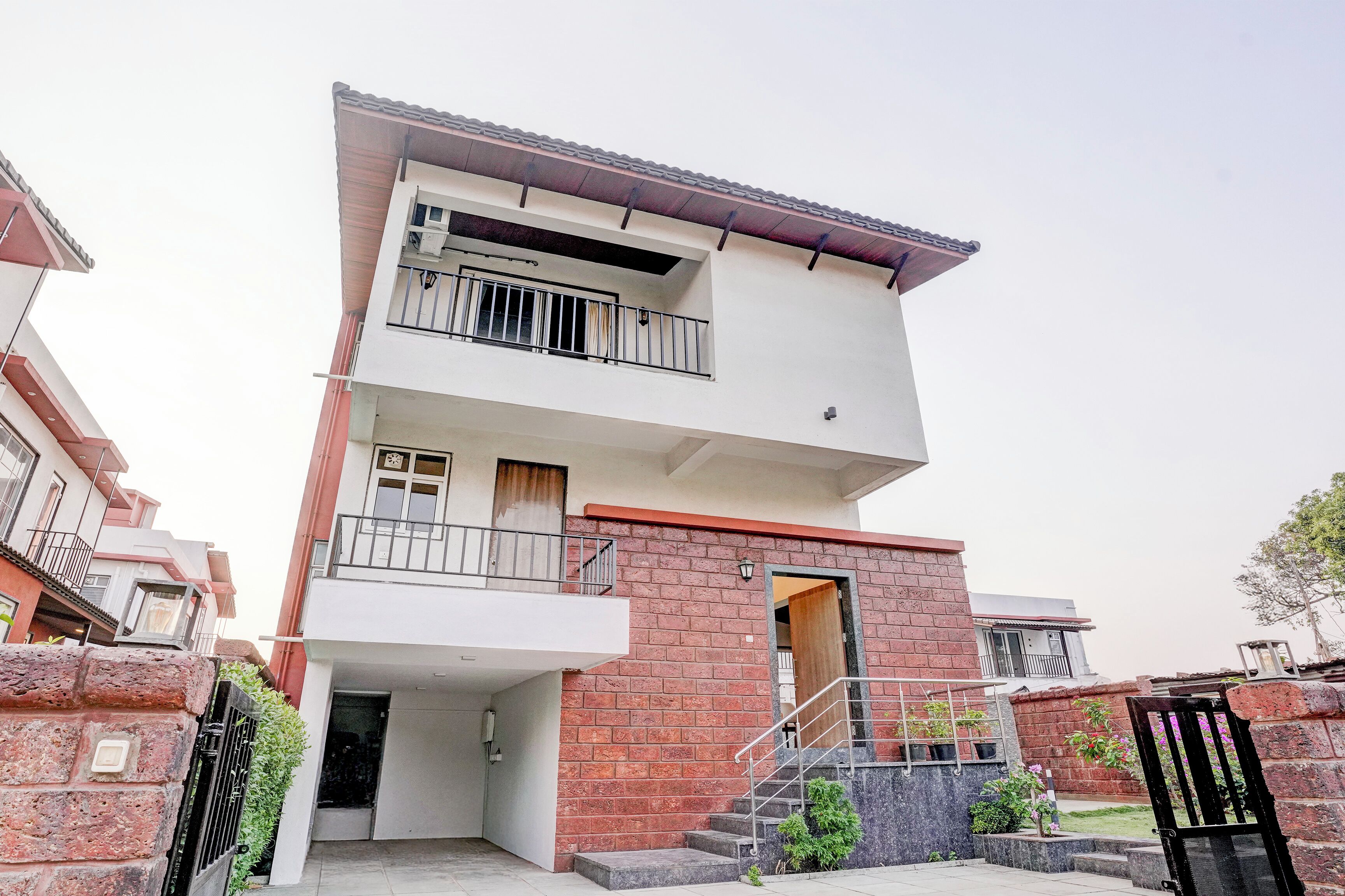 A two-story residential building with a balcony, a staircase, and a gated entrance.