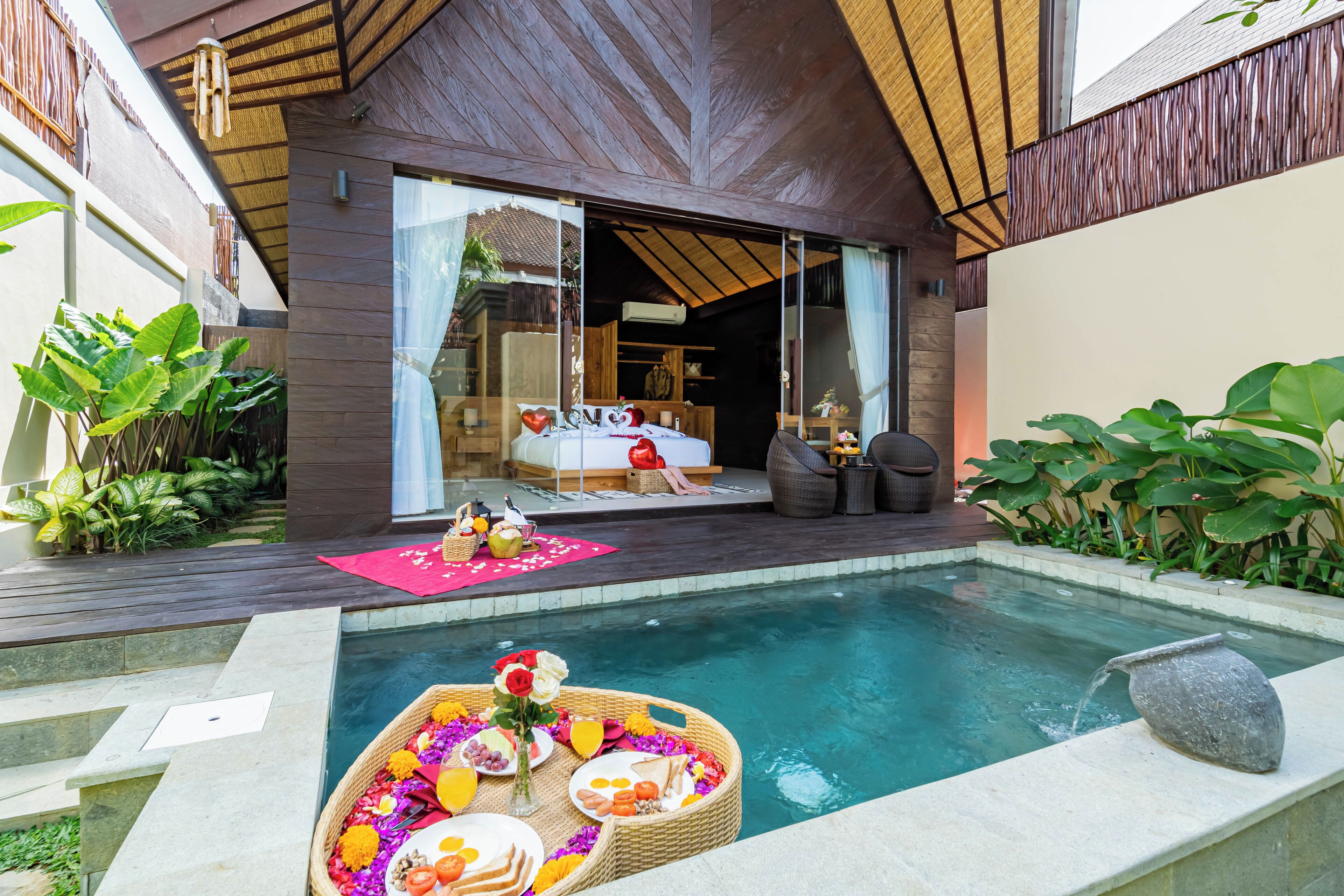 Una villa moderna con piscina, un comedor con mesa para dos y un rincón de estar acogedor con sofá y sillones.